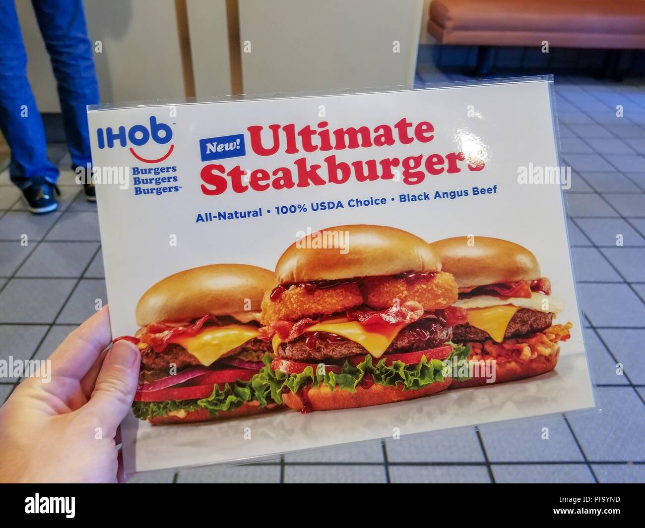 Hand of a man holding a menu with images of several burgers, as well as IHoB (International House of Burgers) logo, following pancake restaurant International House of Pancake's (IHoP) decision to change its name to IHoB, Dublin, California, June 20, 2018. () Stock Photo