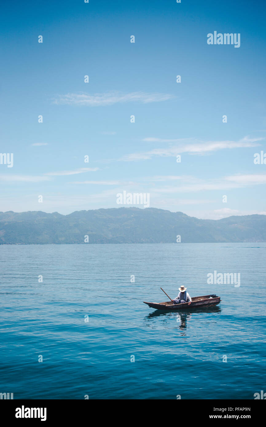 Local Guatemalan fisherman fishes with nets from a small canoe on Lake Atitlán, Guatemala Stock Photo
