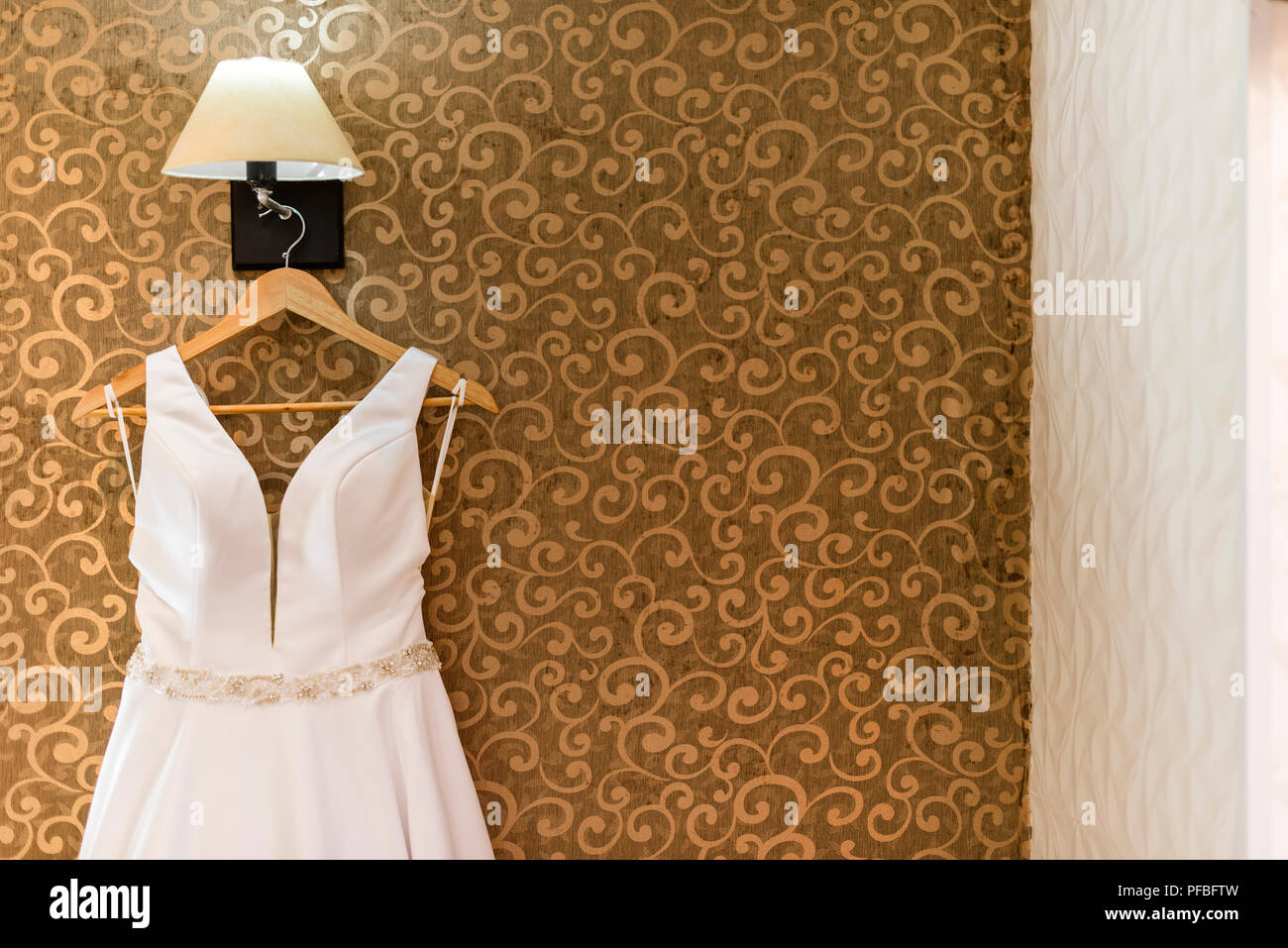 Wedding dress hanging on textured wall Stock Photo - Alamy