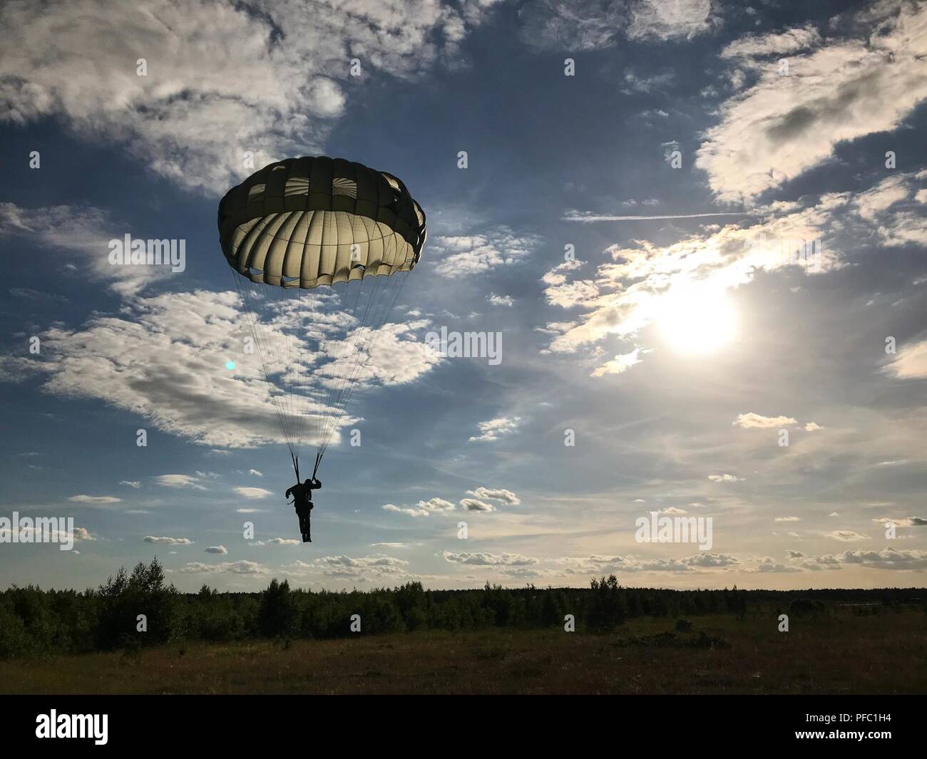 A Lithuanian National Defence Volunteer Force soldiers glides to the ground with members of the Pennsylvania Army National Guard during airborne training at the annual Saber Strike exercise near Rukla, Lithuania, June 7, 2018. This year marks the 25th anniversary of working relations between Lithuania and the state of Pennsylvania as part of a state partnership program. Saber Strike is a multinational exercise scheduled to run from June 3-15 that tests participants from 19 countries on interoperability and each unit's ability to perform its assigned tasks. Stock Photo