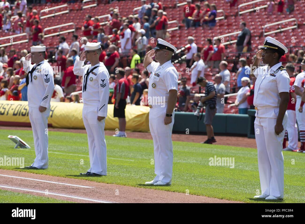 ST. LOUIS (June 7, 2018) – Sailors assigned to Navy Recruiting District St. Louis salute during the playing of the National Anthem at Busch Stadium prior to a baseball game between the St. Louis Cardinals and Miami Marlins. Sailors manned the bases in support of the 60th Cardinal Division pre-game ceremony in which 80 new recruits were sworn into the Navy. The division is named after the St. Louis Cardinals who have sponsored such groups annually since 1958. Stock Photo
