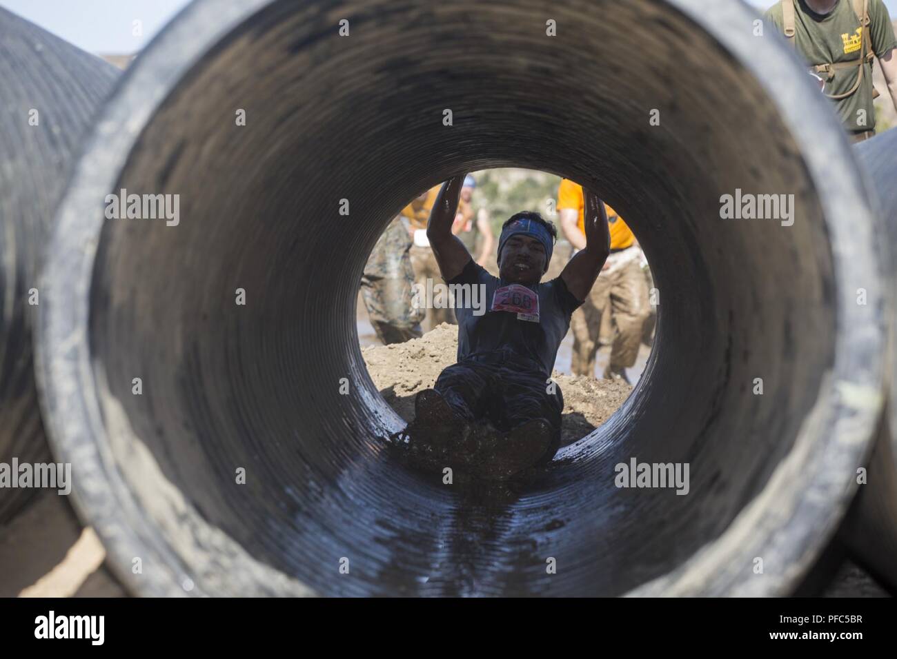 A Marine hurls himself into a tunnel during the 2018 Mud Run Commanding General’s Cup Team Competition, on Marine Corps Base Camp Pendleton, Calif., June 8, 2018. The race stretched over 10-kilometers around Lake O’Neill on MCB Camp Pendleton. Over 2,000 Marines from numerous units around California and neighboring states participated in the challenge. Stock Photo