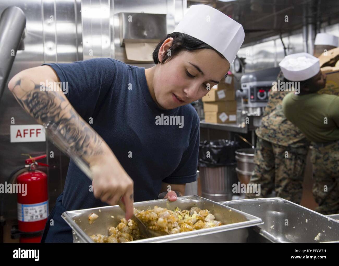 PACIFIC OCEAN (June 7, 2018) Culinary Specialist 3rd Class Elaine Nassar, from Uniontown, Pa., prepares a meal for the crew of San Antonio-class amphibious transport dock USS Anchorage (LPD 23) during composite training unit exercise (COMPTUEX). COMPTUEX is the final pre-deployment exercise which certifies the combined Essex Amphibious Ready Group and the 13th Marine Expeditionary Unit’s abilities to conduct military operations at sea and project power ashore during their upcoming deployment in summer of 2018. Stock Photo