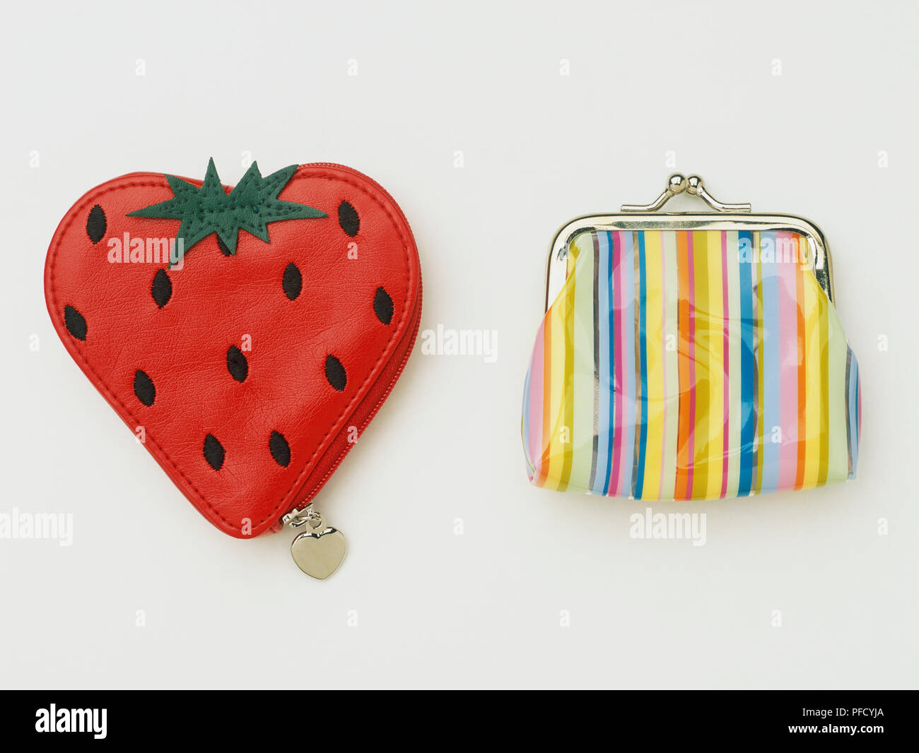 Strawberry-shaped purse and colourful striped purse, close up. Stock Photo