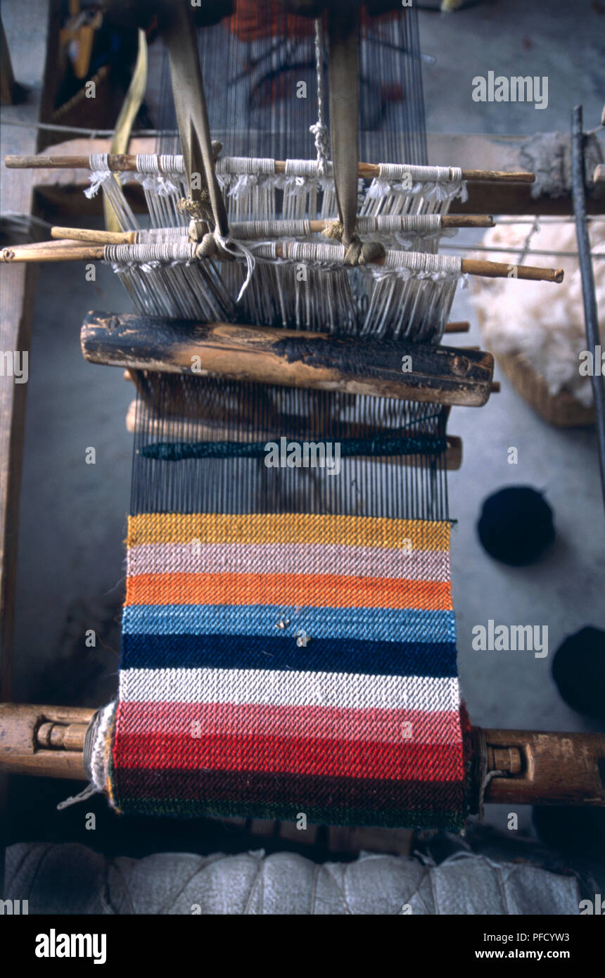 China, Tibet, Tsang Region, Shigatse, Gang Gyen Carpet Factory, colourful striped carpet being woven on a loom. Stock Photo