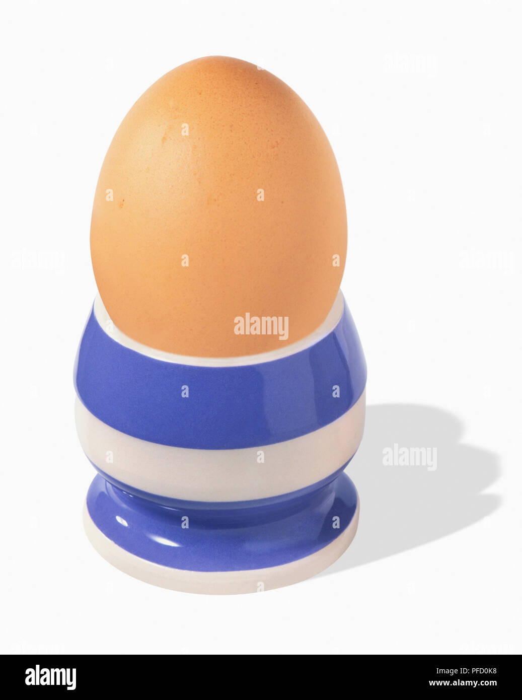 Blue and white striped egg cup and brown egg, front view Stock Photo
