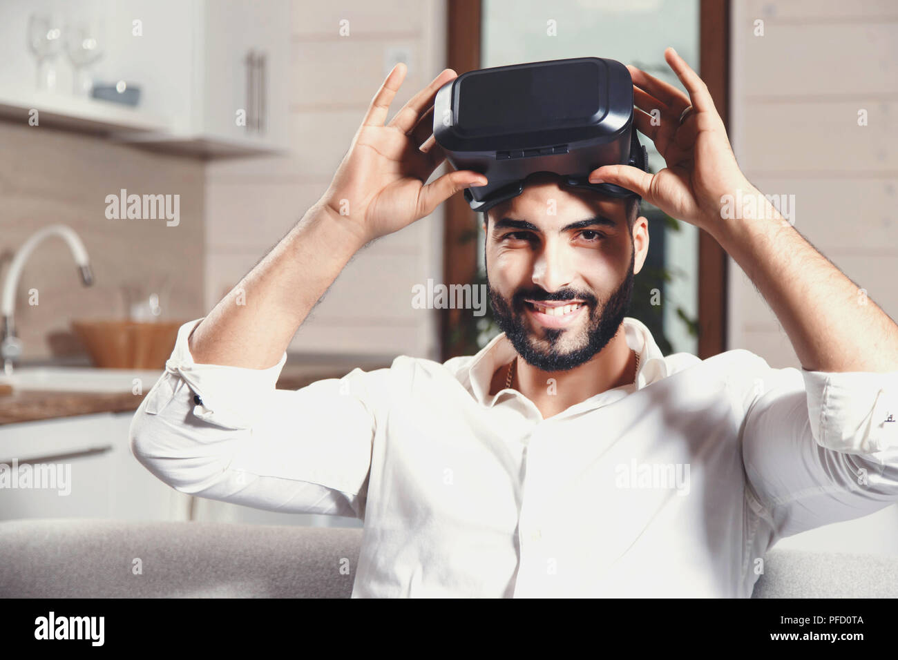Multicultural bearded man using virtual reality goggles in the modern flat Stock Photo