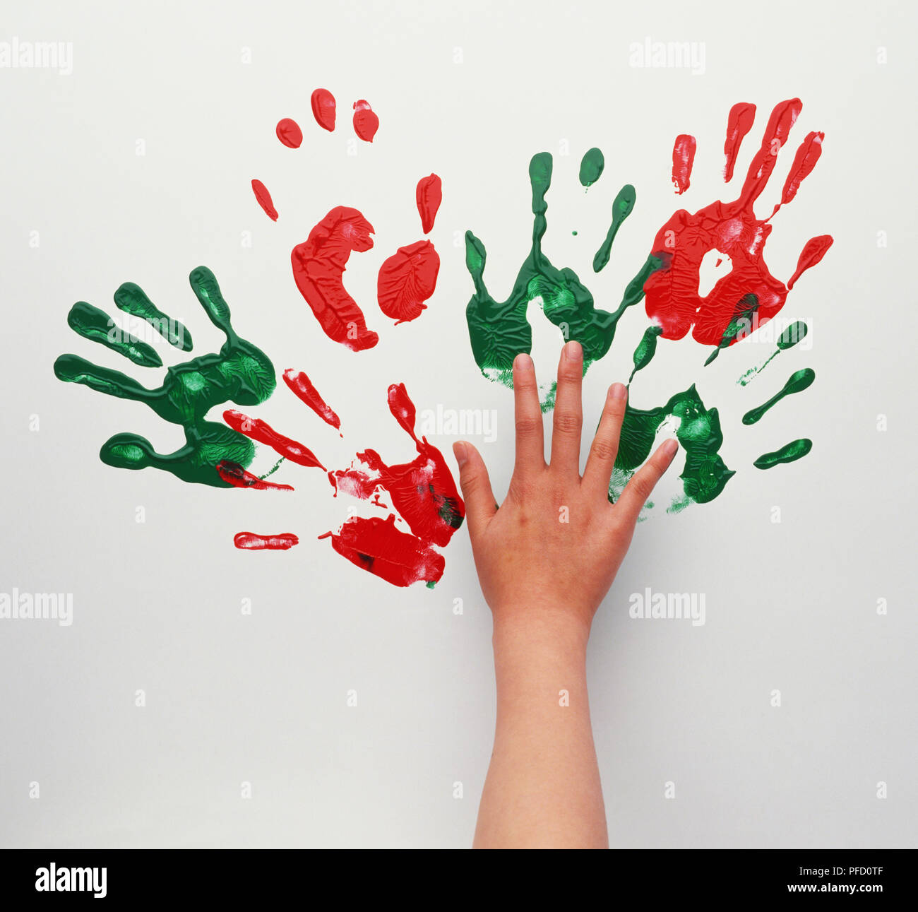 Outstretched hand, green and red watercolour hand shapes on wall. Stock Photo