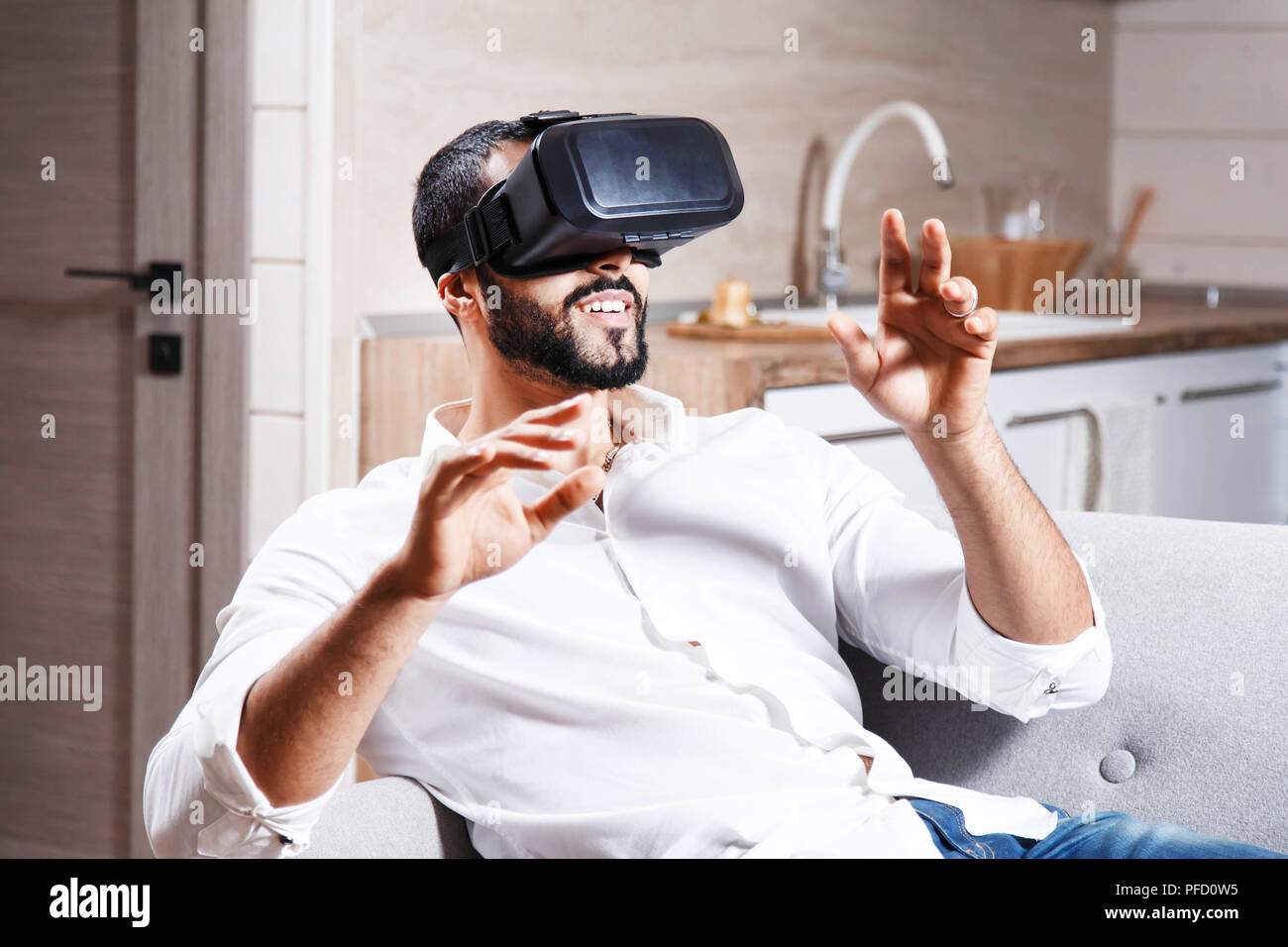 Multicultural bearded man using virtual reality goggles in the modern flat Stock Photo
