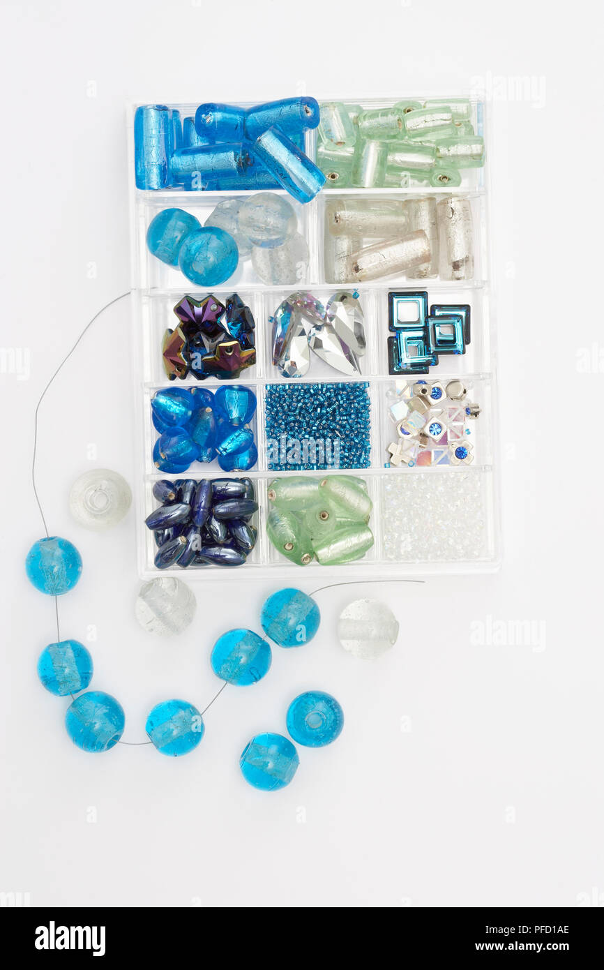 Bead box containing wide variety of differently shaped blue, white, green, clear and purple beads Stock Photo