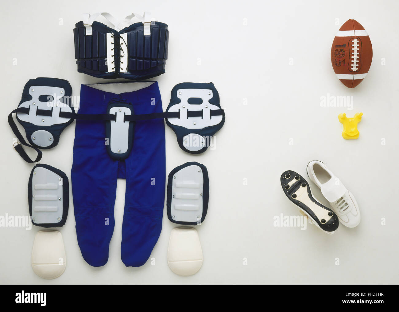 American football ball and uniform, including shoulder pads, hip pads, knee  pads, rib pads and shoes Stock Photo - Alamy