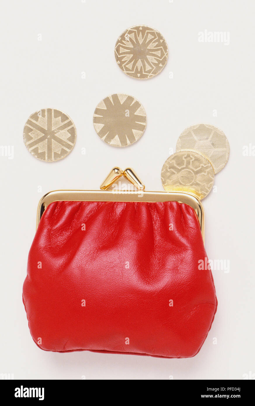 Red leather clasp purse and five toy coins, close up Stock Photo