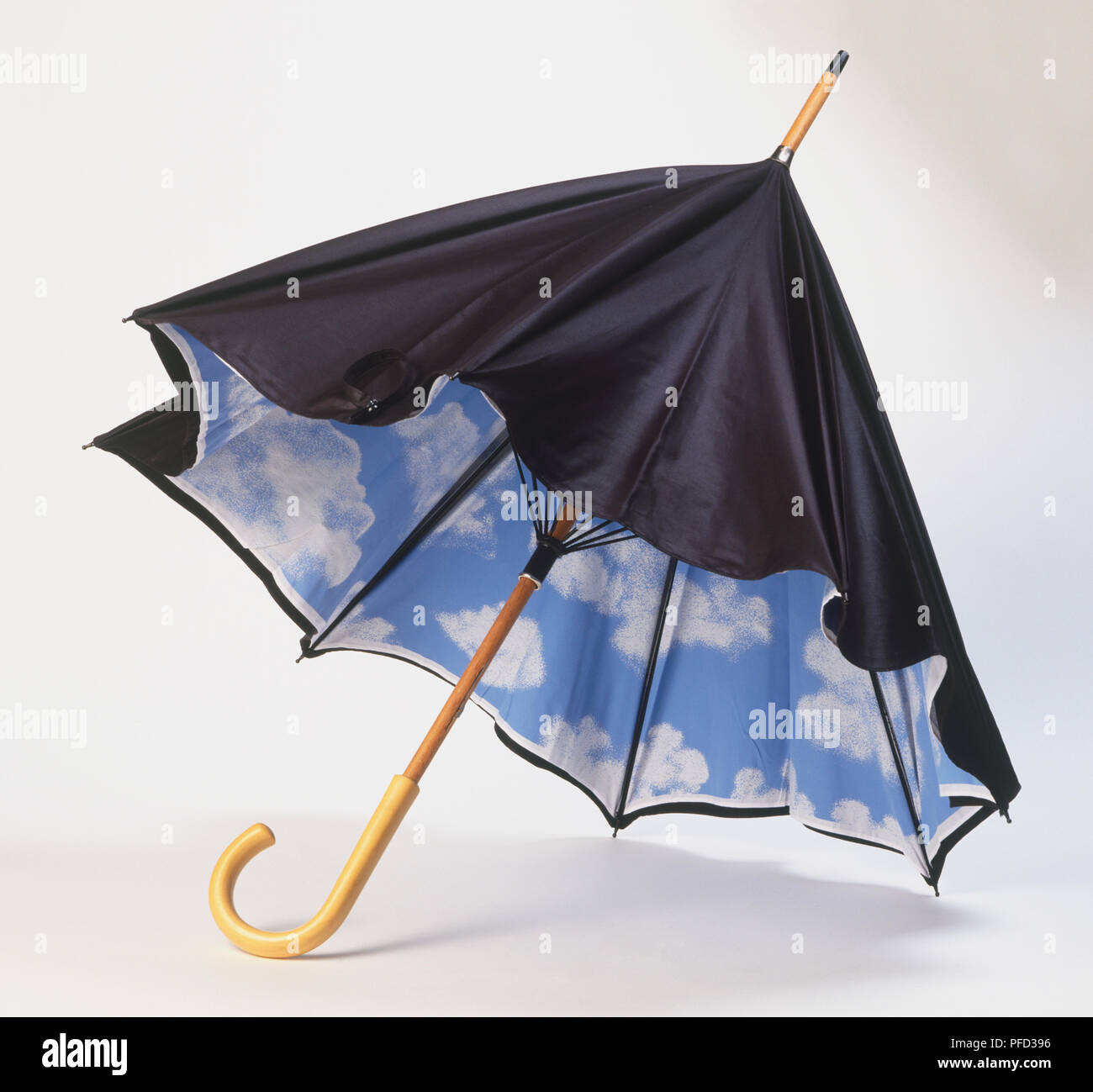 Waxed cotton umbrella with decorated interior showing white clouds on blue sky. Stock Photo