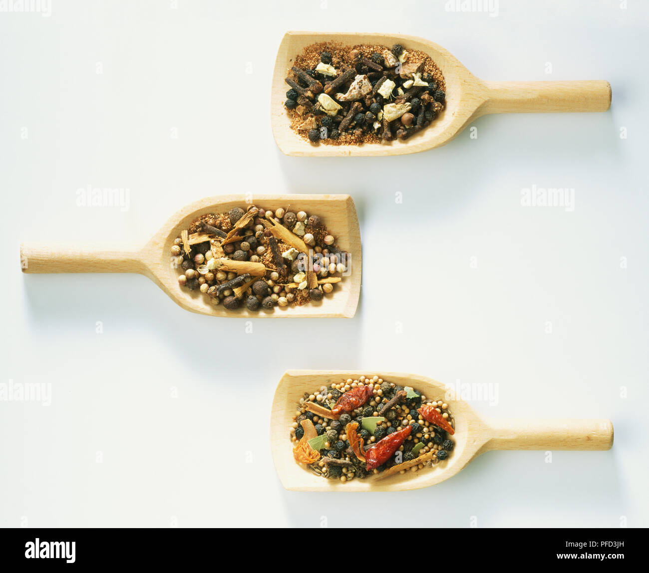 Three spice mixtures displayed on wooden spoons, quatre epices, mixed