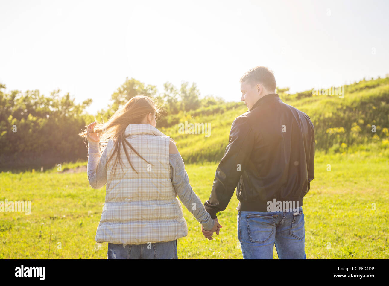Rear view of couple holding hands together and walking in autumn ...