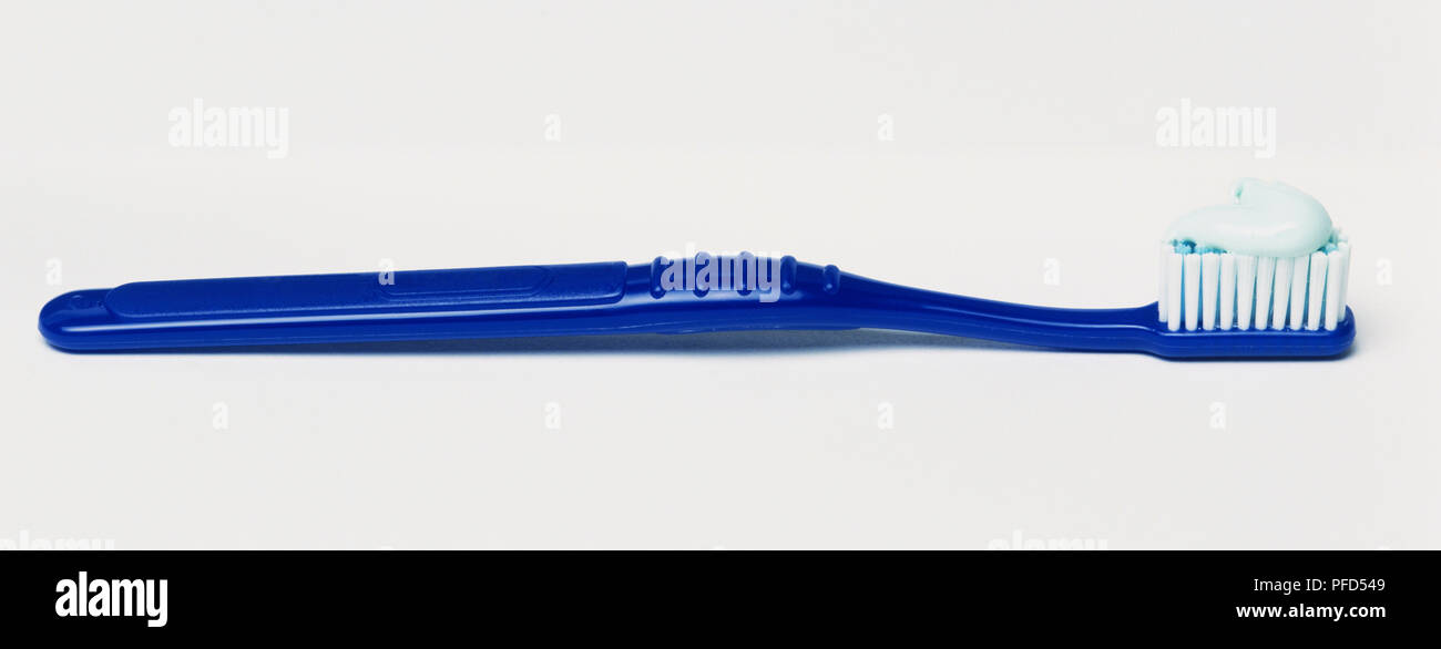 Blue toothbrush with toothpaste on the brush head, side view. Stock Photo