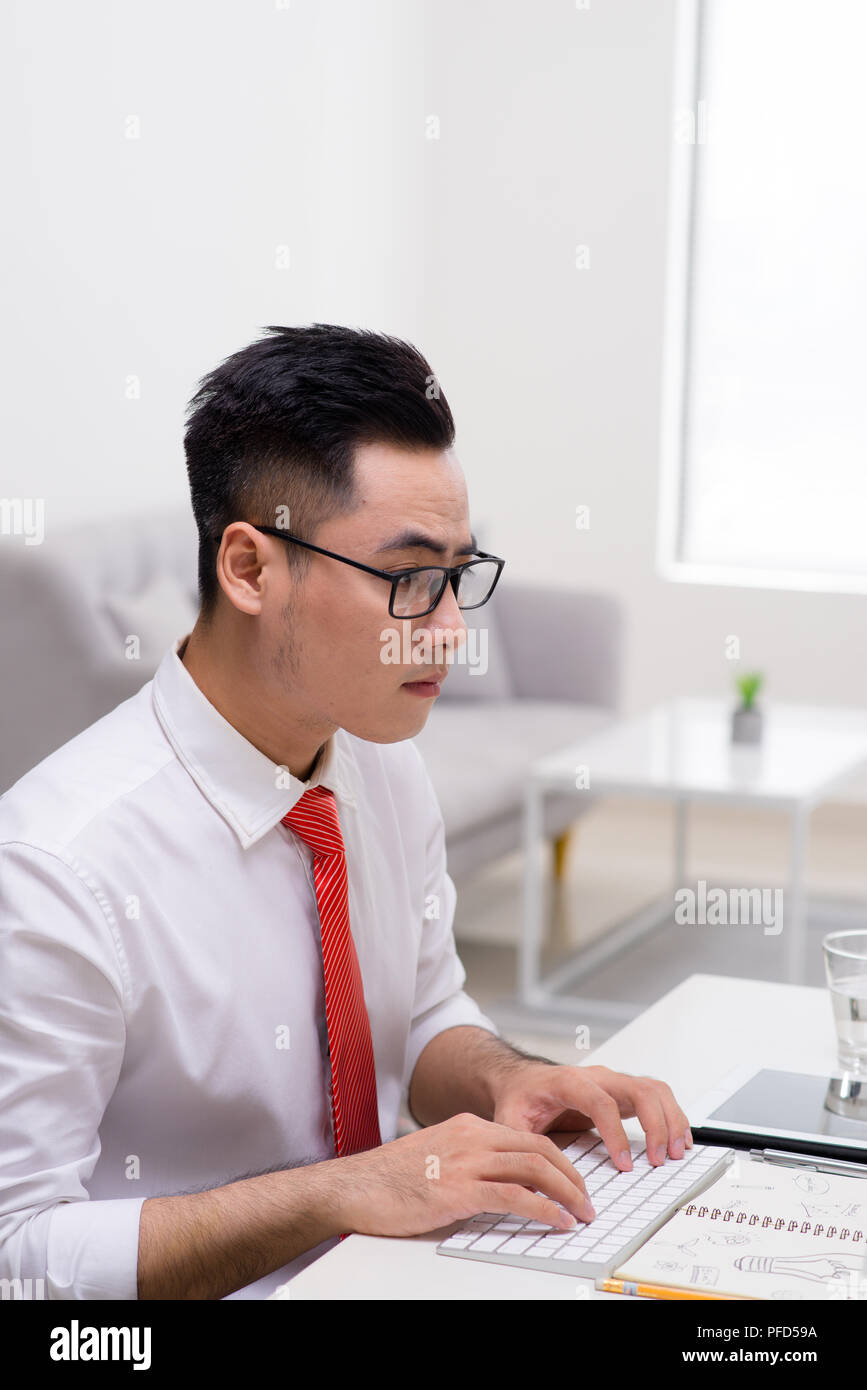 Profile view of a handsome young man doing some meditation exercises while working at the office Stock Photo