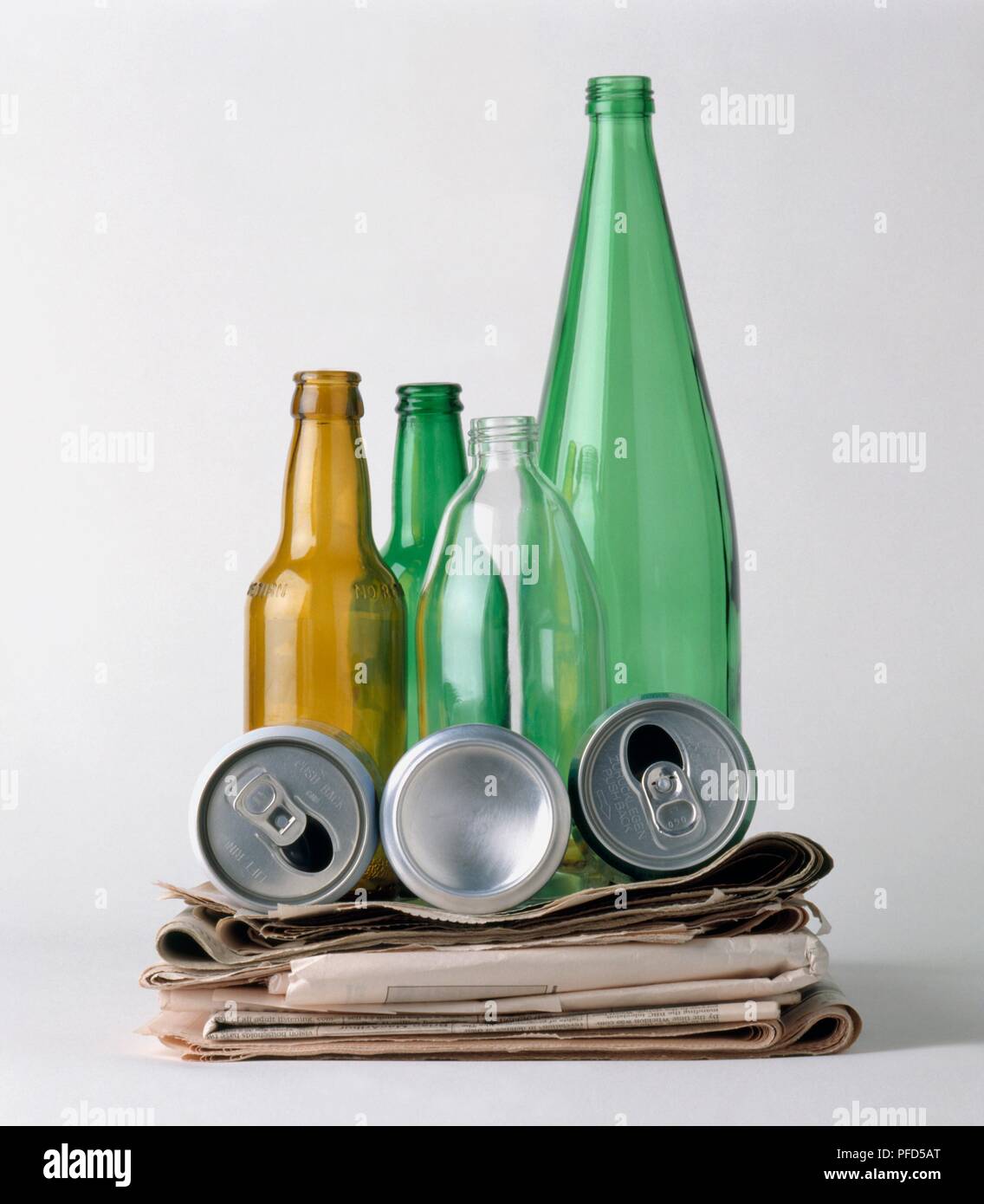 Empty bottles, tin cans and stack of newspapers ready for recycling