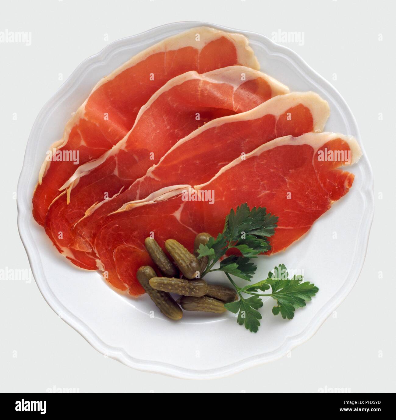 Plate of Ardennes ham with cornichons and sprig of parsley, view from above Stock Photo