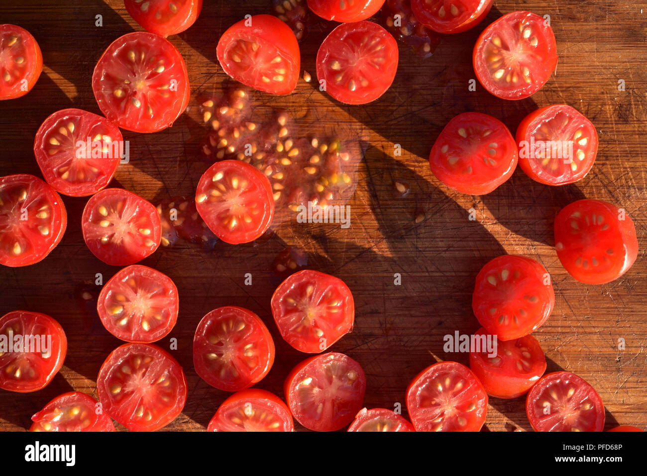 above view of grape tomatoes cut into halves on wood cutting board Stock Photo