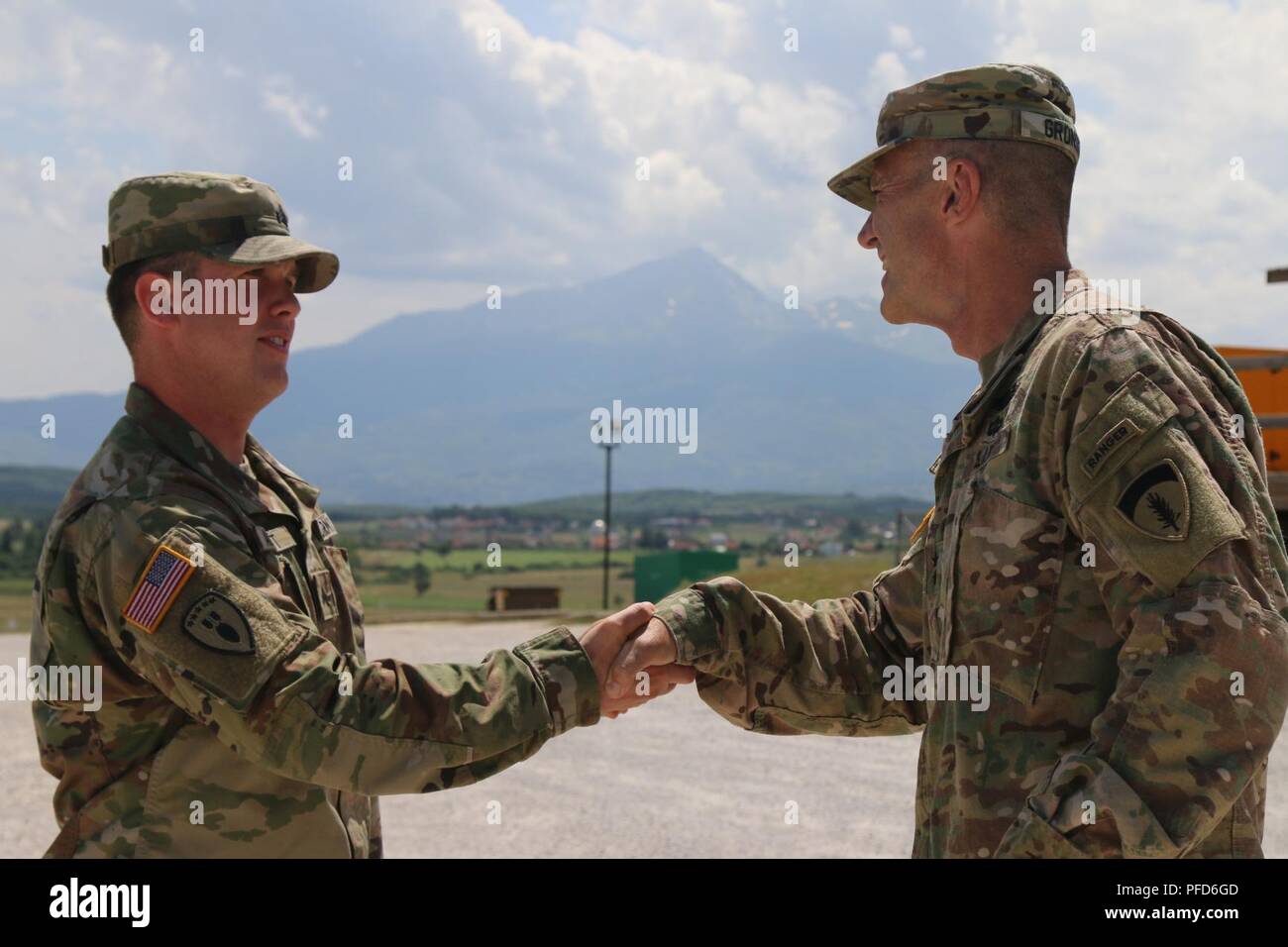 CAMP BONDSTEEL, Kosovo — Maj. Gen. John Gronski, Deputy Commanding General, Army National Guard, United States Army Europe awards a coin to Sgt. Joshua Abbott for his exemplary service with the 702nd Ordnance Company – EOD as an Explosive Ordnance Team Member, June 5. Sgt. Abbott’s contribution to the elimination of unexploded ordnance in Kosovo helps ensure the safety of the people here. Stock Photo