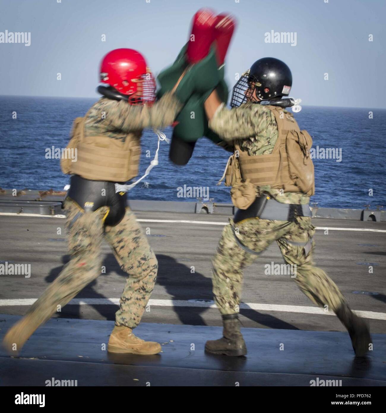 U.S. Marine Lance Cpl. Michael Mitchell, left, a landing support specialist with Combat Logistics Battalion 13, 13th Marine Expeditionary Unit (MEU), and U.S. Navy Seaman Mack Canady, right, square off while at sea during a pugil sticks match aboard the Whidbey Island-class dock landing ship USS Rushmore (LSD 47), June 8, 2018. The Essex Amphibious Ready Group (ARG) and 13th MEU are conducting Composite Training Unit Exercise (COMPTUEX), the final exercise before the units’ upcoming deployment. This exercise validates the ARG/MEU team’s ability to adapt and execute missions in ever-changing, u Stock Photo