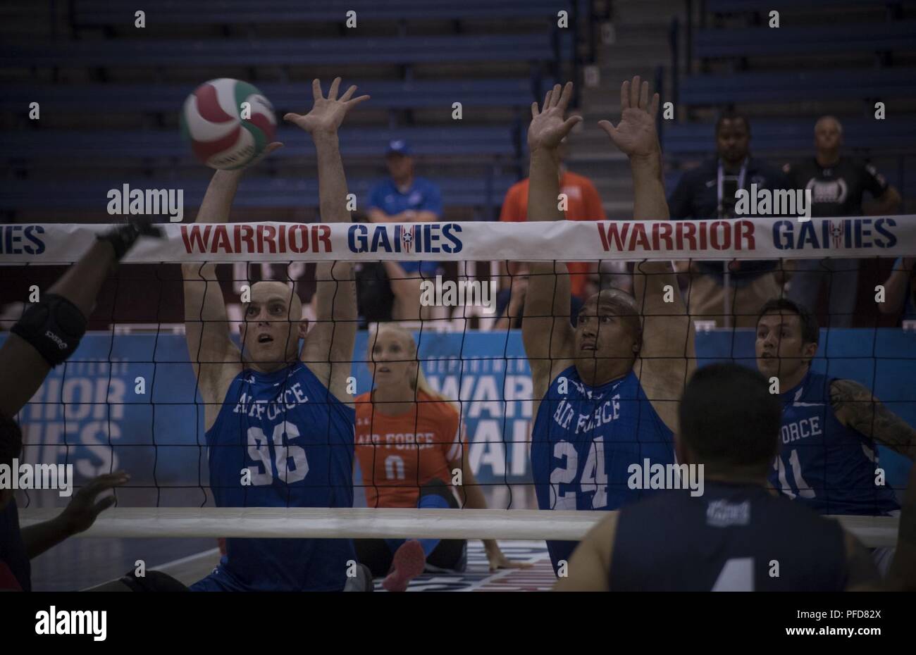 Bill Lickman and Brian Williams, Department of Defense Warrior Games athletes and Team Air Force members, attempt to block a spike by Team Navy during the Department of Defense Warrior Games sitting volleyball championship at the U.S. Air Force Academy, Colorado Springs, Colorado, June 6, 2018. Altogether, 39 Air Force athletes competed in one or more of 11 sports offered at the Games, including archery, cycling, shooting, sitting volleyball, swimming, track and field, and wheelchair basketball, indoor rowing, powerlifting, and time-trial cycling. Stock Photo