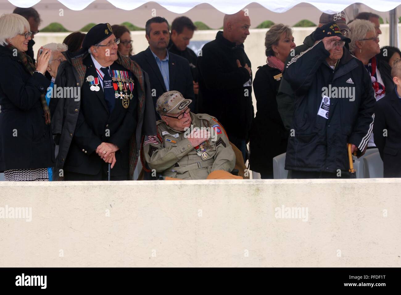 WWII veteran, George Shankle (center), a radio operator with Co. E., 508th Parachute Infantry Regiment, 1st Brigade Combat Team, 82nd Airborne Division, places his hand over his heart as wreaths are laid at the base of a monument during the 74th D-Day commemoration ceremony June 6, 2018 at Utah Beach along the coast of France. Seventy-four years ago to the day, paratroopers, Soldiers, Sailors and Airmen of the United States military conducted the largest assault and changed the tide of WWII. Stock Photo