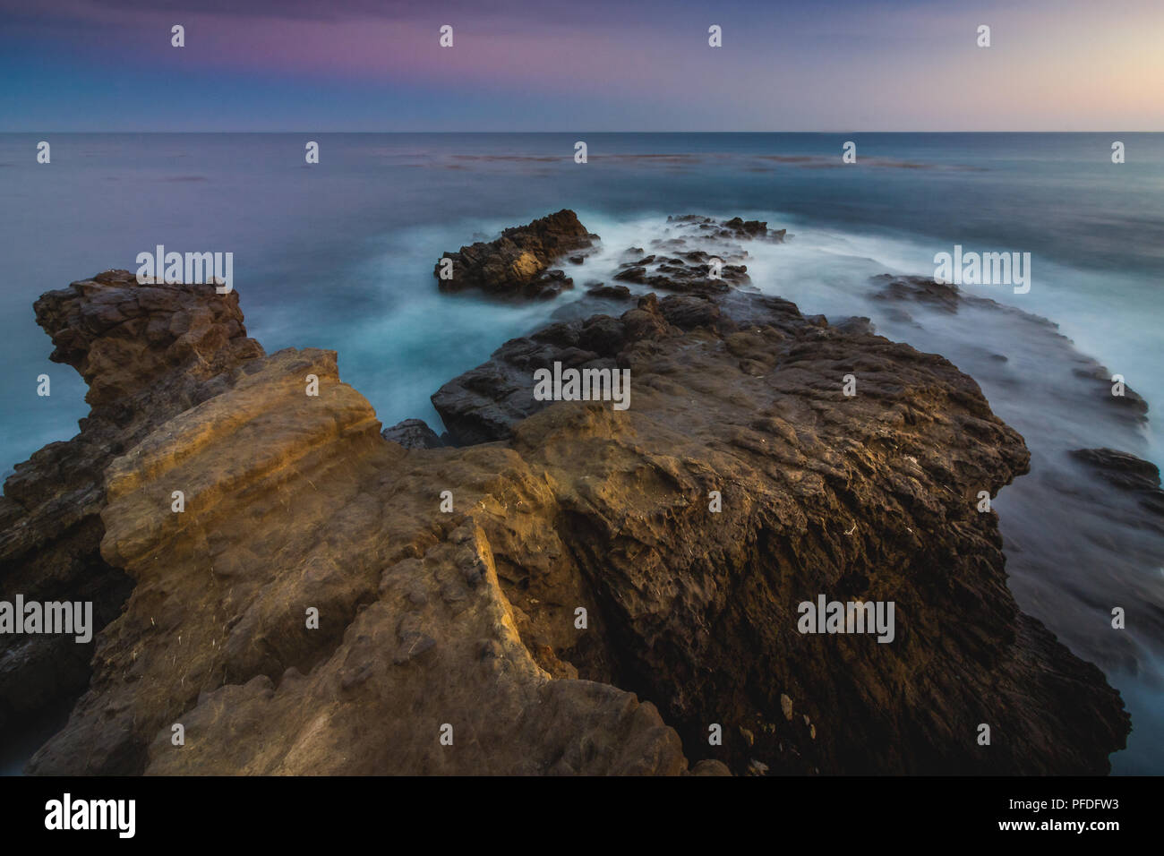 Stunning long-exposure view of smooth waves crashing into rock ...