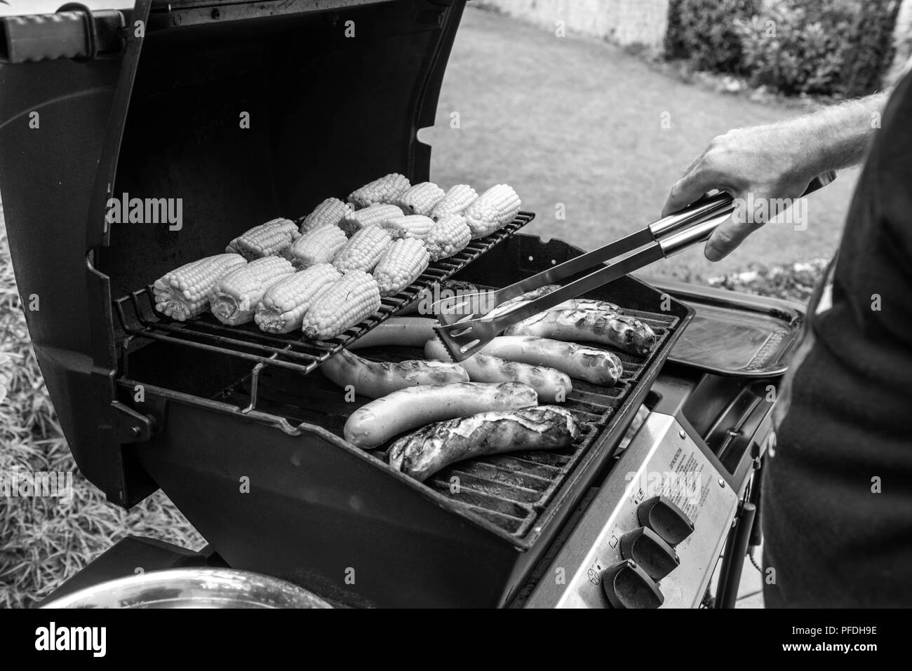 Freshly cooked sausages on a grill with corn close-up. Background of sausages made with charcoal. Stock Photo