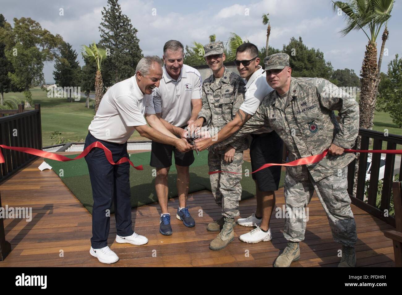 Hodja Lakes Golf Course manager and U.S. Air Force commanders cut the ribbon during a ceremony for the U.S. Air Force’s first elevated tee box at the Hodja Lakes Golf Course, Incirlik Air Base, Turkey, June 12, 2018. The tee box gives golfers a different angle to shoot from, and provides tables and hammocks for leisure. Stock Photo