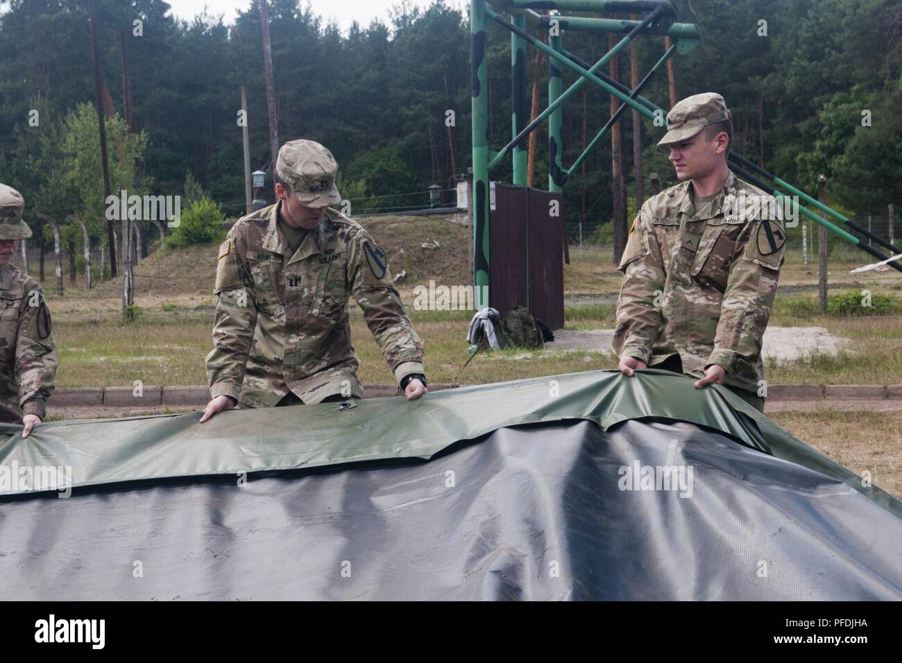 Army Cpl. Ethan Macfarlane, the military intelligence section noncomissioned officer in charge assigned to Headquarters and Headquarters Company, 1st Armored Brigade Combat Team, 1st Cavalry Division, directs Soldiers during the disassembly of the tactical operations center tent during a training exercise in Zagan, Poland, June 12, 2018. Macfarlane is currently deployed in support of Atlantic Resolve in Europe. Stock Photo