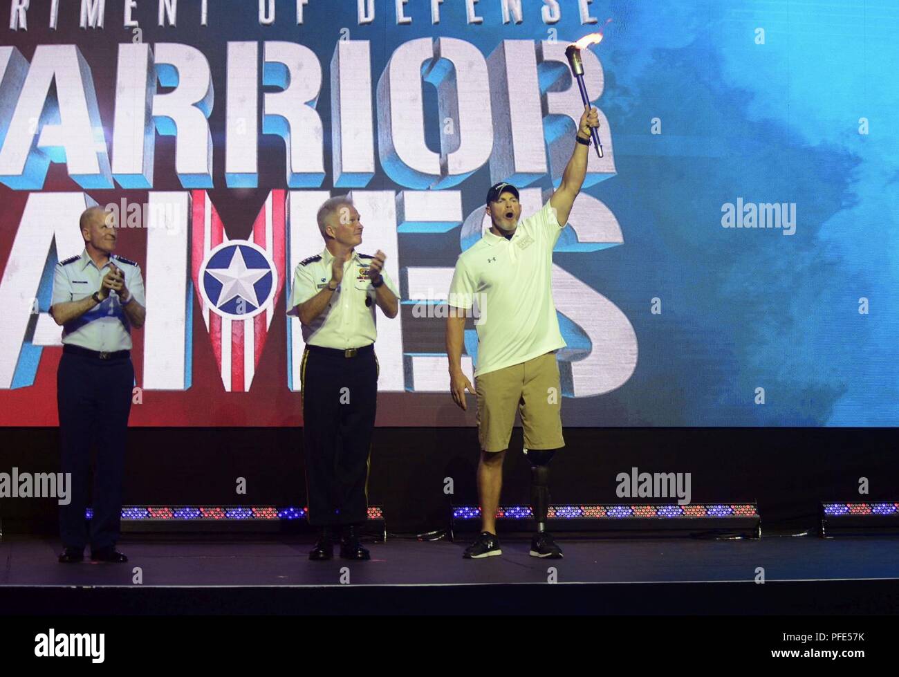 Army Sgt. 1st Class Brant Ireland from Team SOCOM celebrates accepting the flame for 2019 Warrior Games as Army Gen. Raymond A. Thomas III, commander, U.S. Special Operations Command and Gen. Stephen W. Wilson, vice chief of staff, U.S. Air Force applaud during the 2018 Warrior Games closing ceremony held at the Air Force Academy in Colorado Springs June 9, 2018. USSOCOM will host the next Warrior Games in June 2109. Created in 2010, the DoD Warrior Games introduce wounded, ill and injured service members and veterans to Paralympic-style sports. Warrior Games showcases the resilient spirit of  Stock Photo