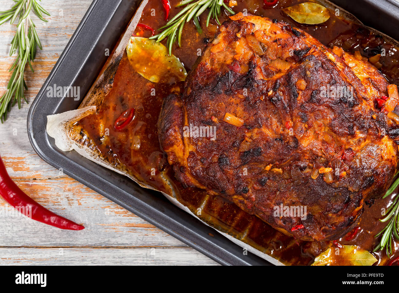 Whole roast shoulder of pulled pork in roasting pan with rich spicy hot
