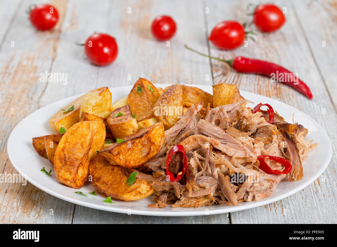 pulled slowcooked pork shoulder grilled in oven with fried potato wedges, chili pepper and