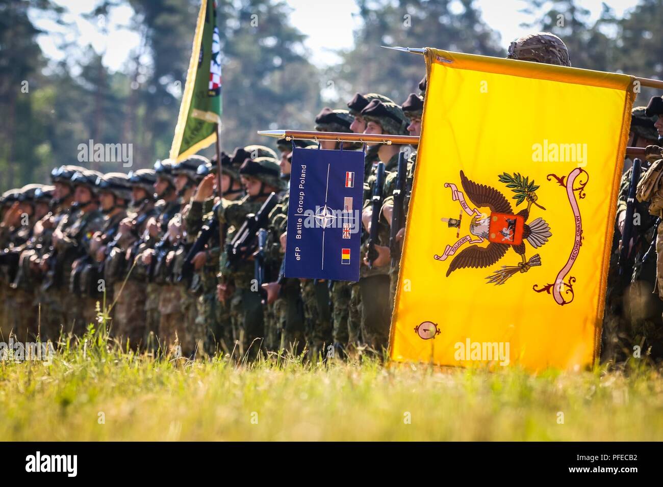 The flag for the Battle Group Poland (left) and the regimental colors for 2nd Cavalry Regiment (right), are held a formation of soldiers during the  opening ceremony of Saber Strike 18 with Battle Group Poland at Wierzbiny, Poland, June 4, 2018. Saber Strike is a multinational exercise currently in its eighth year. This year's exercise, which runs from June 3-15, tests allies and partners from 19 countries on their ability work together to deter aggression in the region and improve each unit's ability to perform their designated mission. Stock Photo