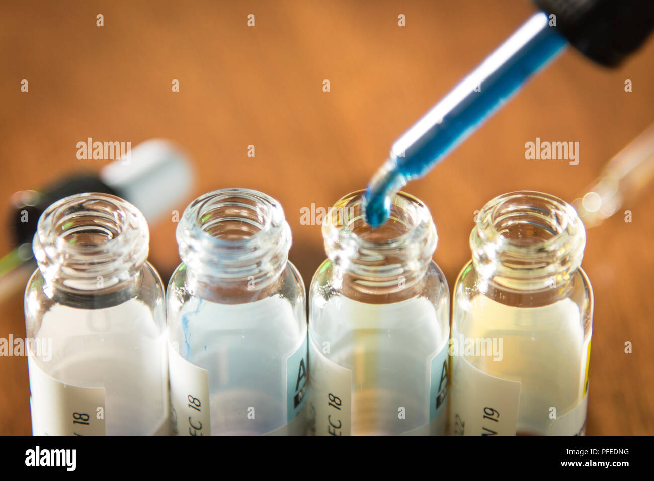 Laboratory glass items adding drop to one of several test tubes. A scientific experiment in a