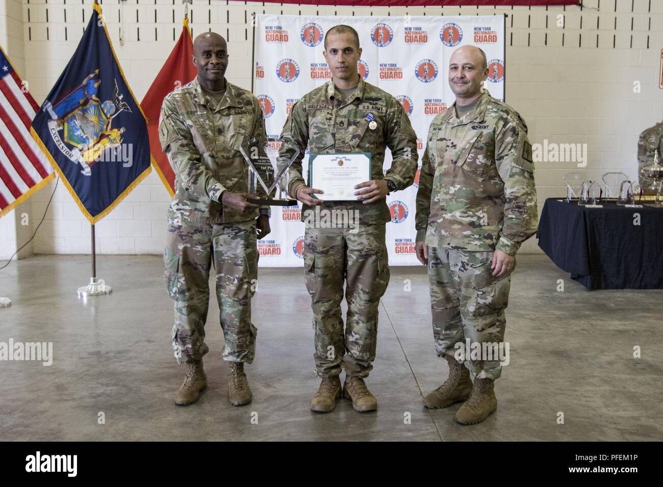 U.S. Army Staff Sgt. Matthew Melendez, an infantryman assigned to Headquarters Company, 1st Battalion, 69th Infantry Regiment, New York Army National Guard, receives an Army Achievement Medal and the Sgt. Thomas Baker Individual Combat Pistol Match 1st Place Award from Brig. Gen. Michel Natali, commander of the 53rd Troop Command, and Command Sgt. Maj. Corey Cush, senior enlisted advisor of the 53rd Troop Command, New York Army National Guard, following the 39th Annual Adjutant General’s Marksmanship Competition at Camp Smith Training Site, N.Y., June 3, 2018. The three-day event features mult Stock Photo