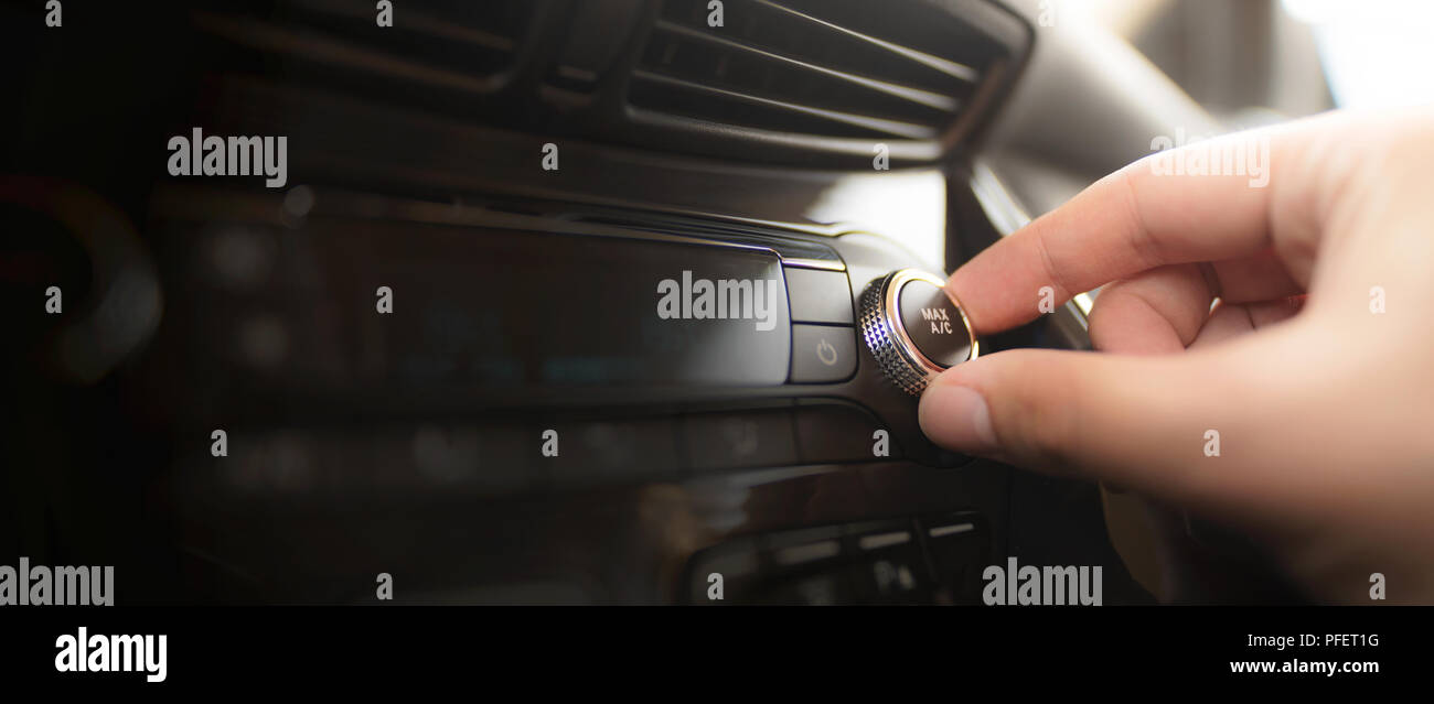 Man turning on car air conditioning system. Air conditioning button