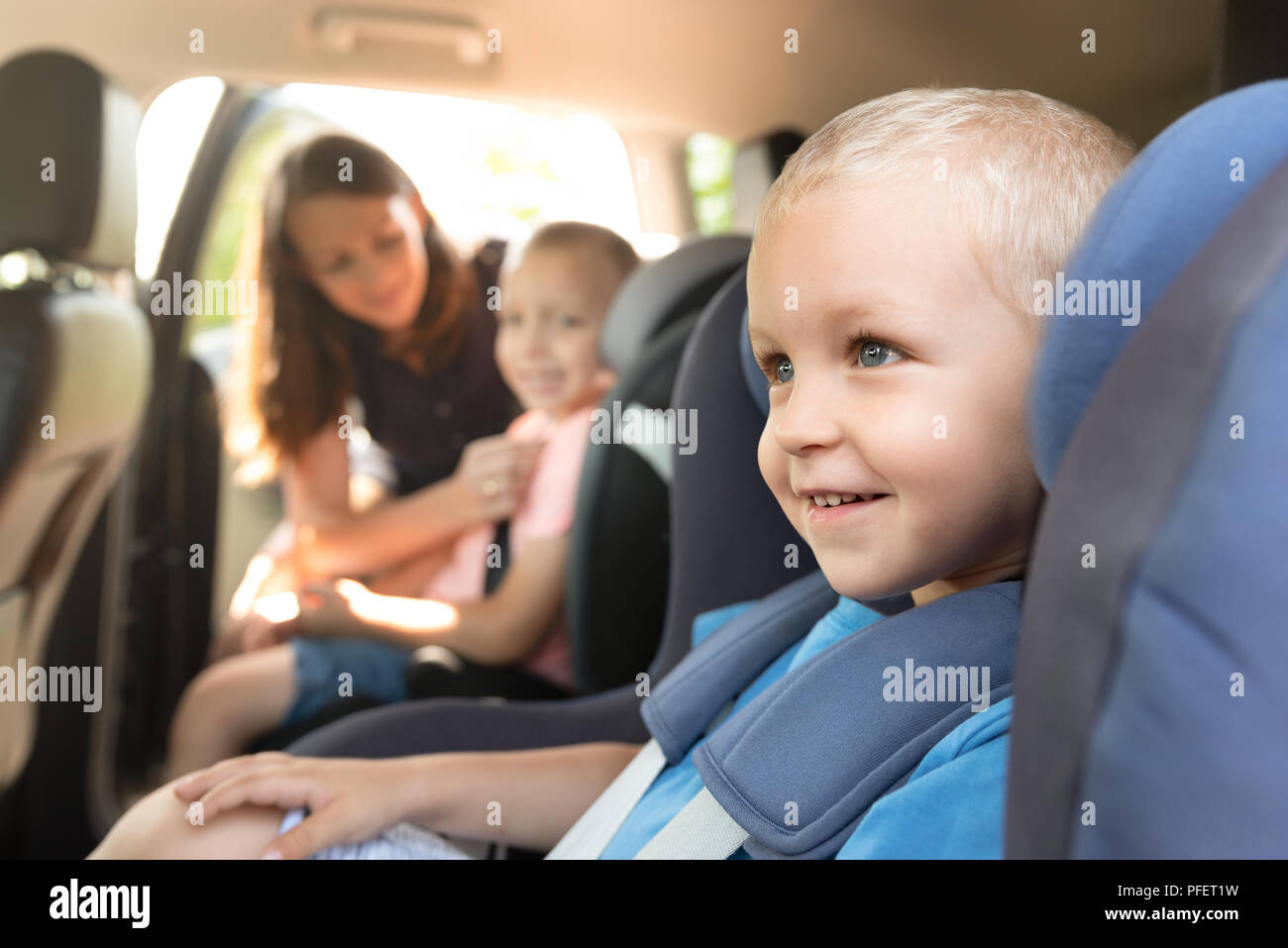 Boys buckled into car seat. Mother takes care about her children in a car. Safe family travel concept Stock Photo