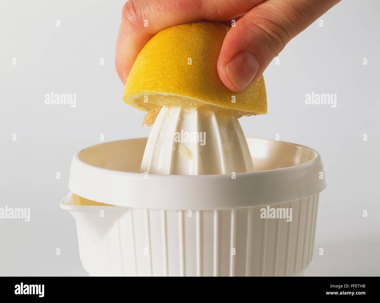 Half a lemon being squeezed over a lemon juicer Stock Photo Alamy
