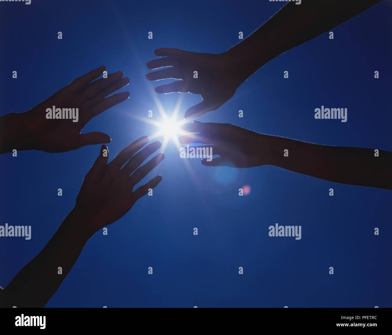 Two pairs of hands reaching out to each other, with beam of sunlight in ...