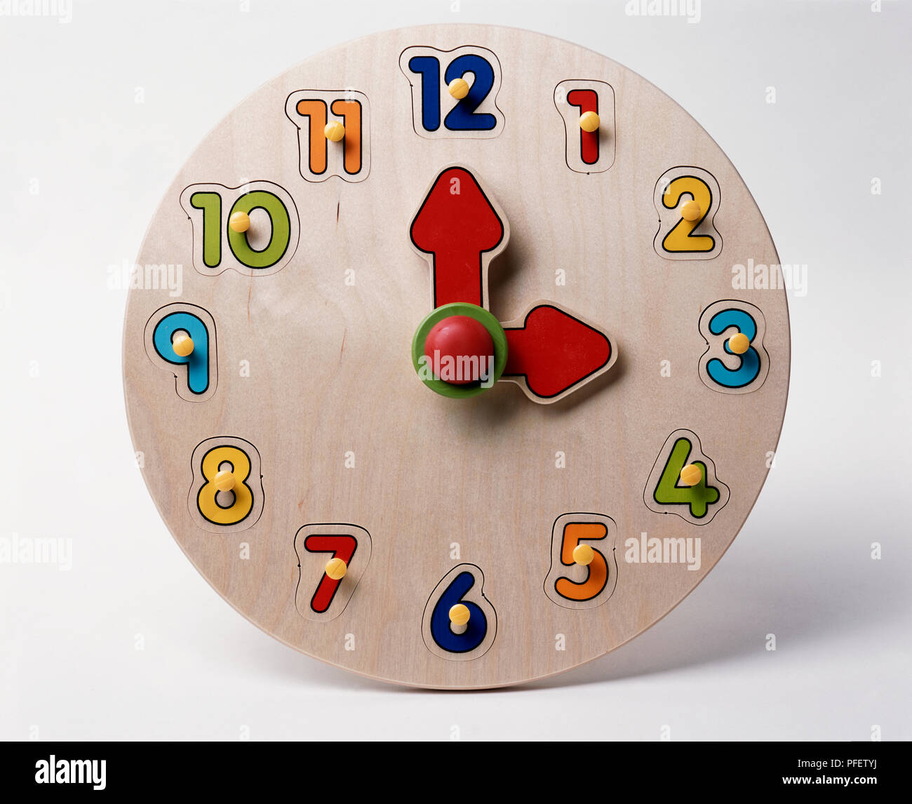 Wooden clock face with clear numbers and bright red hands, showing the time as three o'clock. Stock Photo
