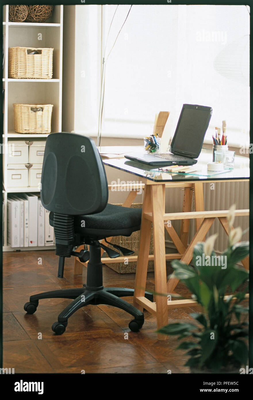 Chair with adjustment levers and desk with lap-top computer. Stock Photo