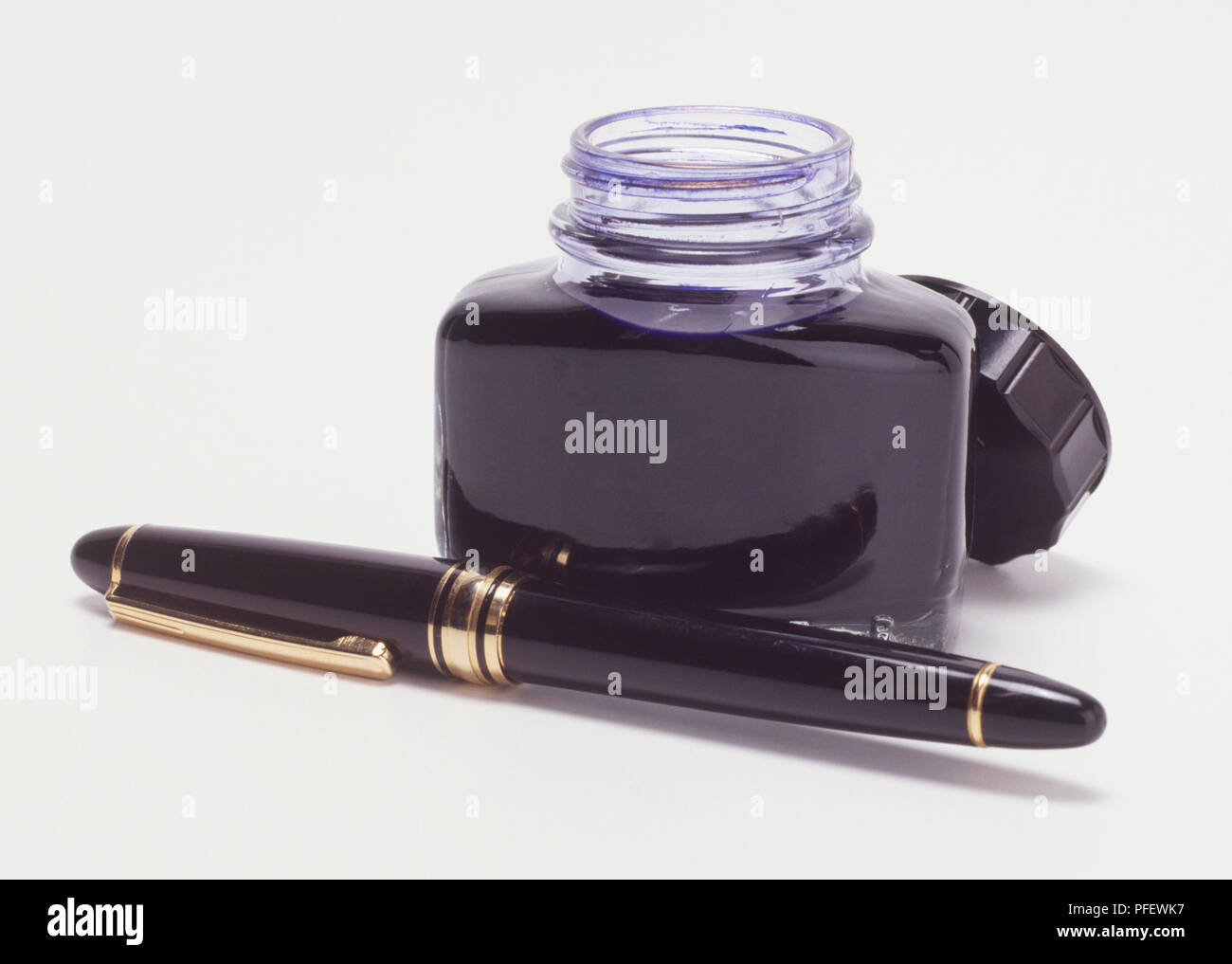 Lidded fountain pen and opened pot of black ink, close up. Stock Photo