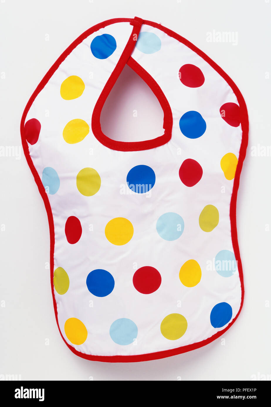 Baby bib with colourful polka dots and red trim, front view Stock Photo