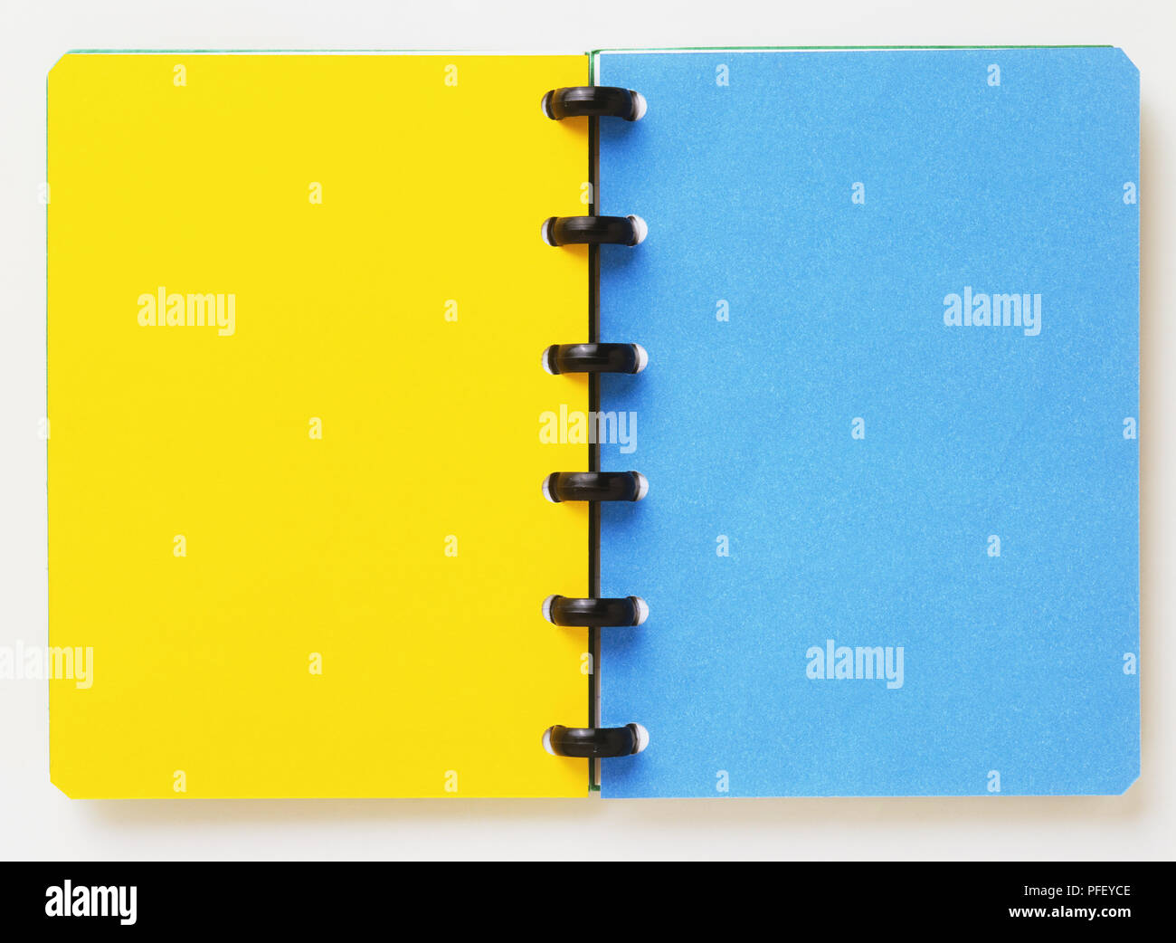 Open spiral-bound notebook, showing a yellow and a blue page Stock Photo