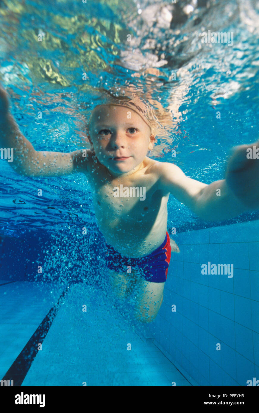 Boy swimming underwater with his eyes open, facing forward Stock Photo