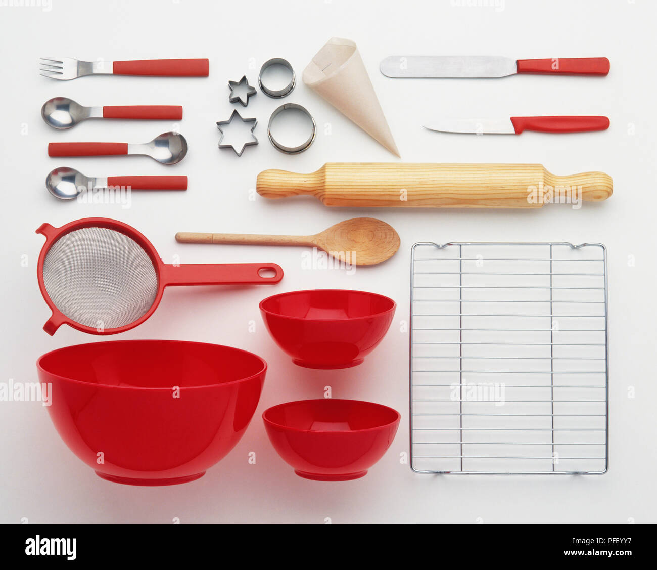 Baking utensils, including bowls, sieve, rolling pin, funnel, wooden spoon, wire rack, cookie cutter, cutlery Stock Photo