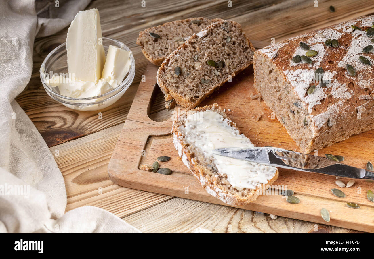 Homemade rye bread with pumpkin seeds and butter. Breakfast concept Stock Photo